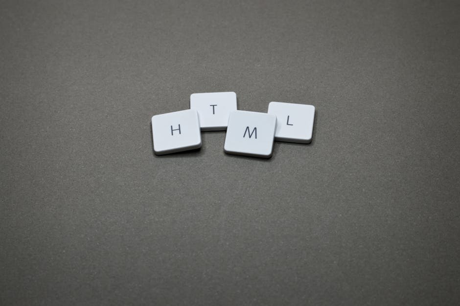 A close-up image of five small, white, rectangular tiles with slightly rounded edges, arranged on a smooth, matte gray surface. Each tile features a single black letter, spelling out 'H', 'T', 'M', 'L